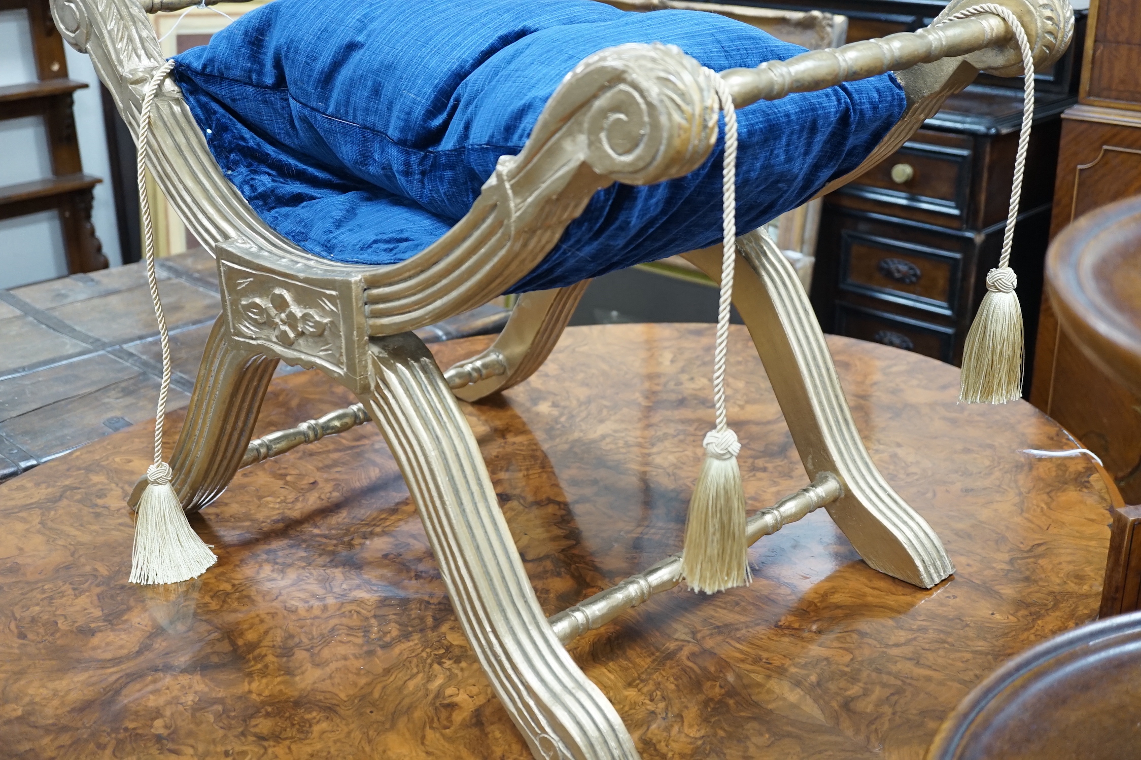 A Regency style carved and fluted giltwood x-frame stool, width 76cm, depth 47cm, height 52cm